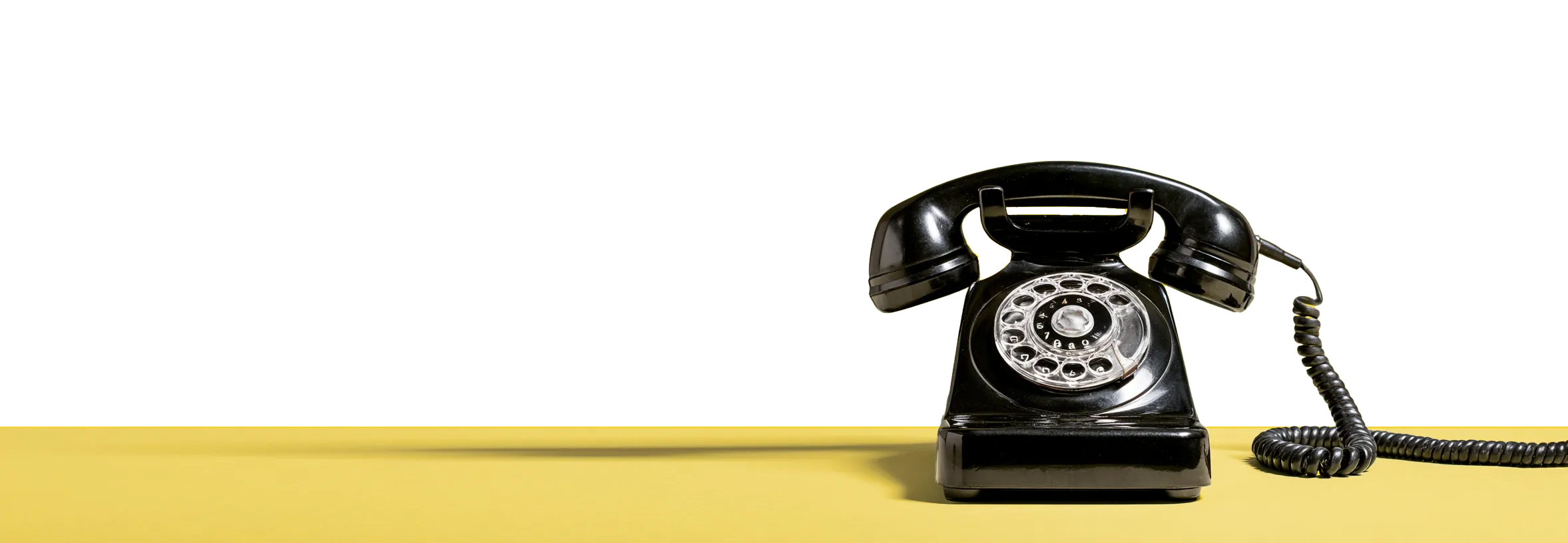 Telefon retro negru așezat pe o suprafață galbenă